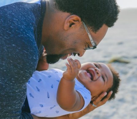 Photo by Lawrence Crayton man in blue sweater kissing woman in white and blue polka dot shirt on beach during