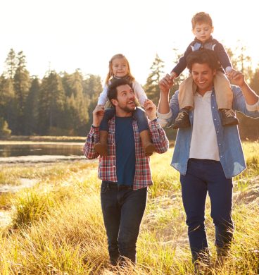 Gay,Male,Couple,With,Children,Walking,By,Lake